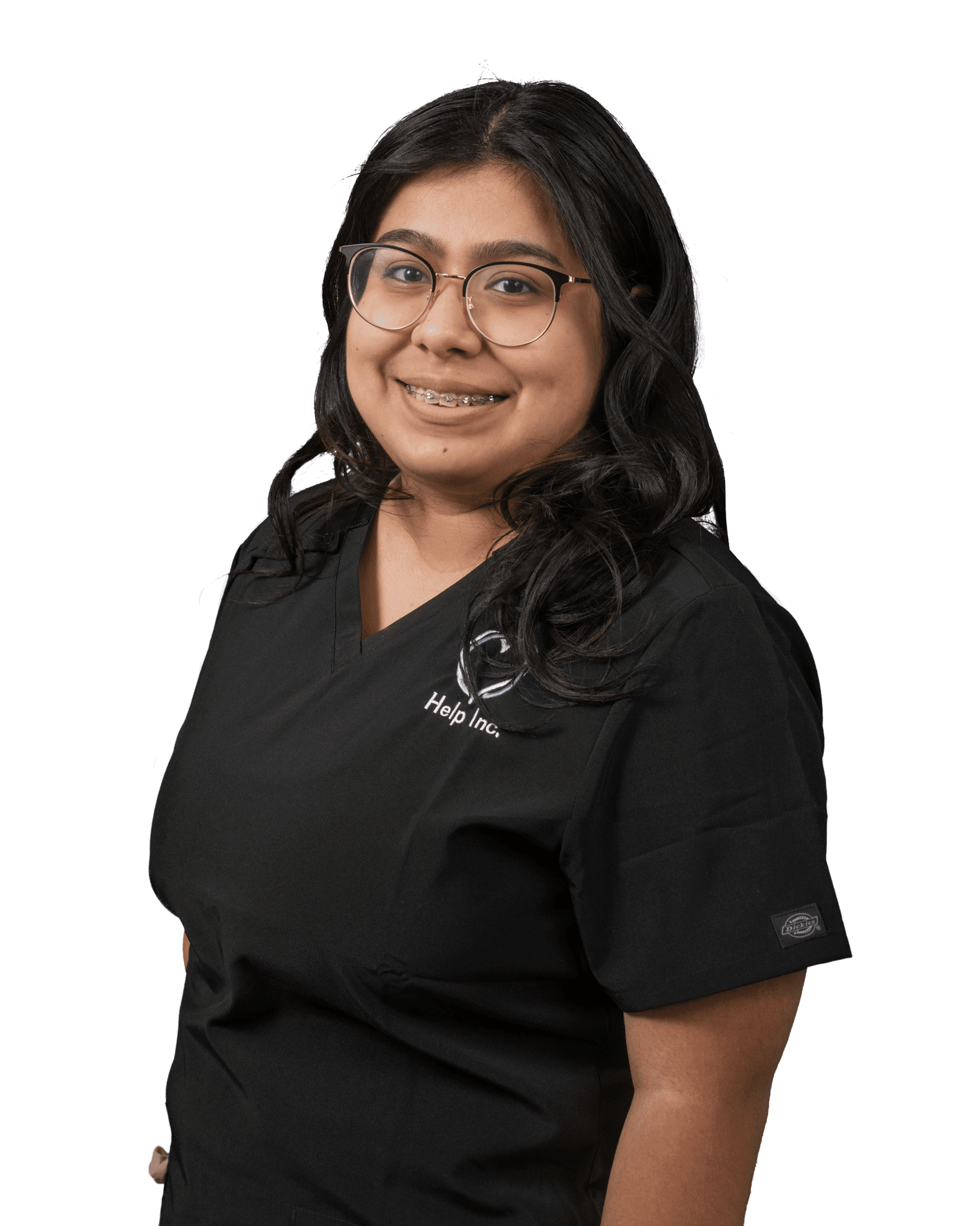A woman wearing glasses and black medical scrubs with "Help Inc." embroidered on the top, smiling and facing the camera.