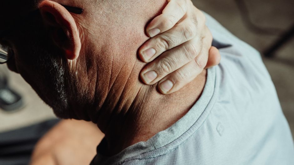 A senior holding the back of their neck to manage chronic pain.